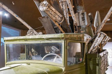 Muhtemelen 20. yüzyılın ortalarından kalma, iyi korunmuş bir zeytin yeşili askeri kamyon, bir müzede ya da sergide sergilenmektedir. Kamyon, büyük kalibreli makineler de dahil olmak üzere çeşitli silahlarla donatılmıştır.