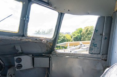 Pas ve renk değişimlerini gösteren metal bir duvarı olan eski bir araç kulübesinin iç görüntüsü. Sol taraftaki büyük bir pencereden gelen doğal ışıklandırma.