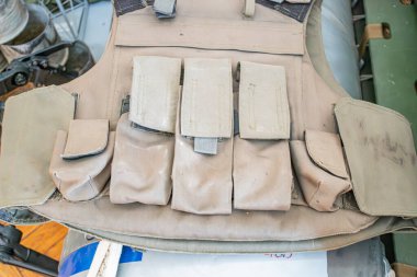 Birden fazla cepli zeytin yeşili askeri kurşun geçirmez yelek, ayarlanabilen tozlu kayışlar borular ve mekanik aydınlatma ile endüstriyel arka plan yumuşak gölgeler Pe