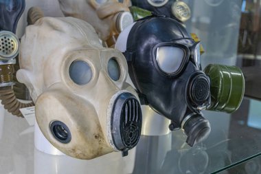 Cam bir kutuda sergilenen özet antika askeri gaz maskesi. Tasarım, renk ve yaşlanma bakımından üç farklı maske.