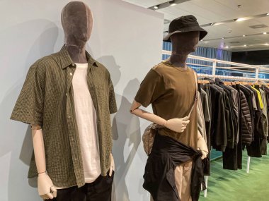 Ukrayna askeri üniforma görüntüsü, katmanlı iki manken, daha soğuk hava kıyafetleri, açık ve koyu renk kombinasyonları, yumuşak gölgeler, desenli arka plan duvarı, geniş açı fotoğrafçılık, temiz bir hava.