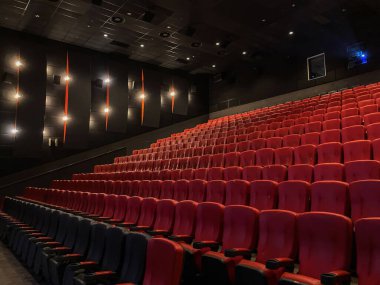 Aydınlatılmamış VIP sinema salonu. Geniş, koyu renkli, kırmızı koltuklu. Çok sayıda tavan lambası, gündelik bir sahneyi tasvir eden, çeşitli ışıklandırma seçenekleri sunuyor.