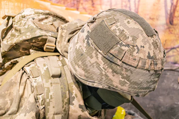 Kamuflaj üniformalı bir askerin profil görüntüsü, miğfer, sırt çantası, muhtemelen açık hava, gündüz, doğal ışık. a