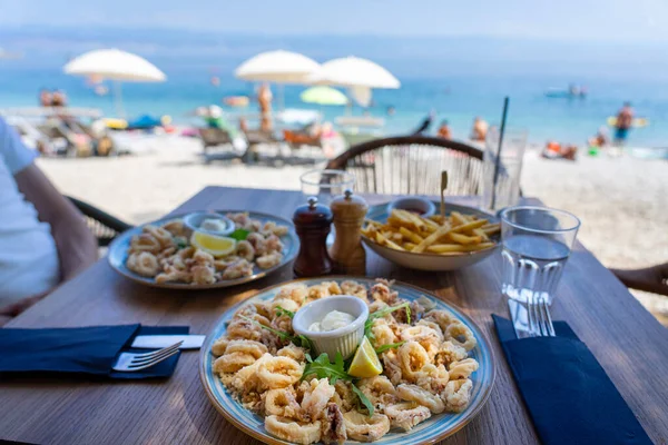 Hırvat sahil barından deniz manzaralı kızarmış kalamar yemek. .