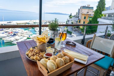 Hırvatistan 'da balkondan deniz manzaralı kızarmış kalamar yemek ve içecekler. .