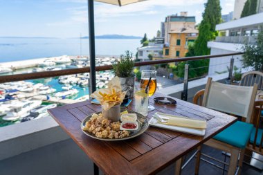 Hırvatistan 'da balkondan deniz manzaralı kızarmış kalamar yemek ve içecekler. .