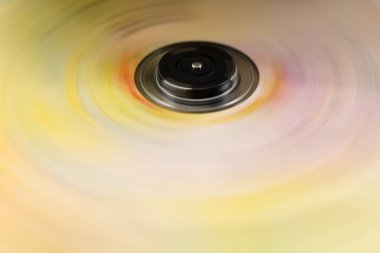 Canlı sarı ve pembe hareket bulanıklığı olan dönen kompakt diskin soyut yakın çekimi renkli bir dairesel arkaplan ve dinamik fütüristik etki yaratır..