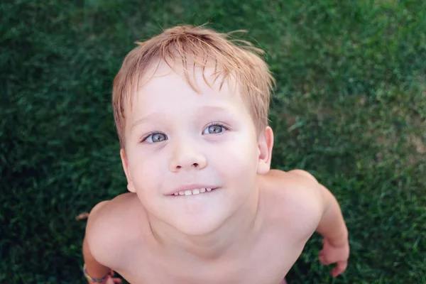 Kleinkind sitzt auf Gras und blickt in die Kamera — Stockfoto