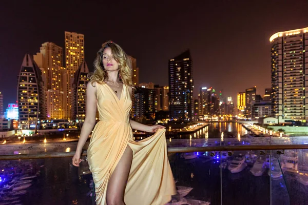 Mujer en Dubai Marina, Emiratos Árabes Unidos. Una dama atractiva con un vestido largo. Chica admirando Marina vista por las noches —  Fotos de Stock