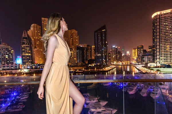 Mujer en Dubai Marina, Emiratos Árabes Unidos. Una dama atractiva con un vestido largo. Chica admirando Marina vista por las noches —  Fotos de Stock