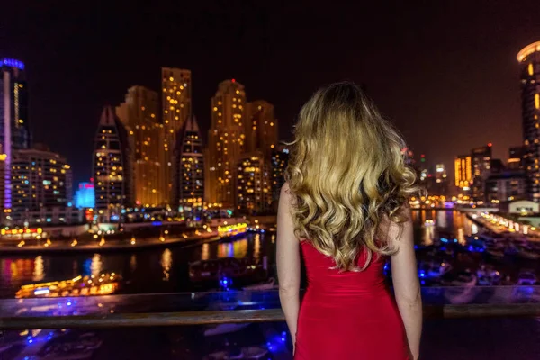 Frau in Dubai Marina, vereinigte arabische Emirate. attraktive Dame in einem roten Kleid. Mädchen bewundert Yachthafenblick in der Nacht — Stockfoto
