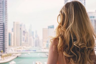 Dubai Marina 'daki kadın, Birleşik Arap Emirlikleri. Marina 'nın gündüz manzarasına hayran uzun elbiseli çekici bir bayan.