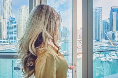 Dubai Marina 'daki kadın, Birleşik Arap Emirlikleri. Marina 'nın gündüz manzarasına hayran uzun elbiseli çekici bir bayan.