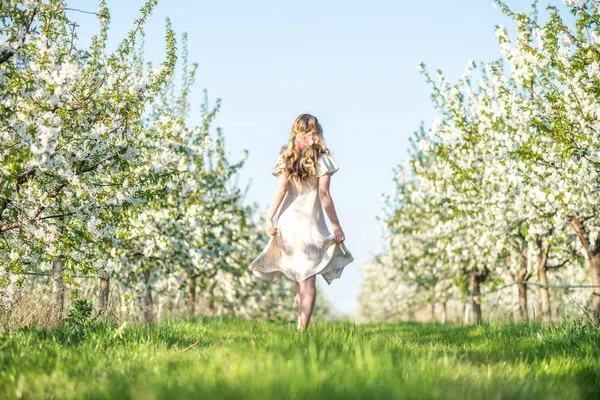Mujer en un huerto floreciente en primavera. Disfrutar de un día soleado y caluroso. Ropa de estilo retro. Humores de primavera llenos de color —  Fotos de Stock