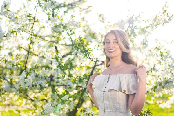 Woman in a blooming orchard at springtime. Enjoying sunny warm day. Retro style dress. Colorful spring moods — Stock Photo, Image