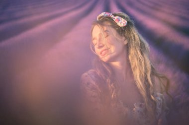 Lavanta tarlasında yaz elbisesi giymiş bir kadın. Hayalperest bir portreyi yakından çek.