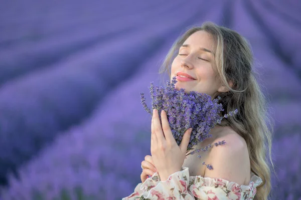 女人闻到薰衣草花束的味道 快乐的梦幻般的微笑夏装漂亮卷曲的头发 — 图库照片