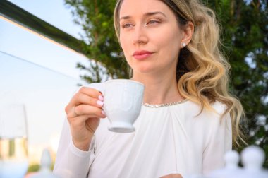 Mutsuz kadın bir fincan kahve içiyor. Açık teras öğle yemeği. Beyaz elbiseler