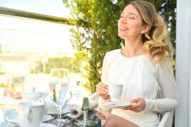 Terasta kahve içen ve manzaranın tadını çıkaran bir kadın. Restoranlarda kahvaltı mı kahvaltı mı?