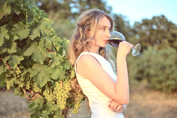 Bir bardak şarabı olan bir kadın rüya gibi görünüyor, şarap içen mutlu bir kız.