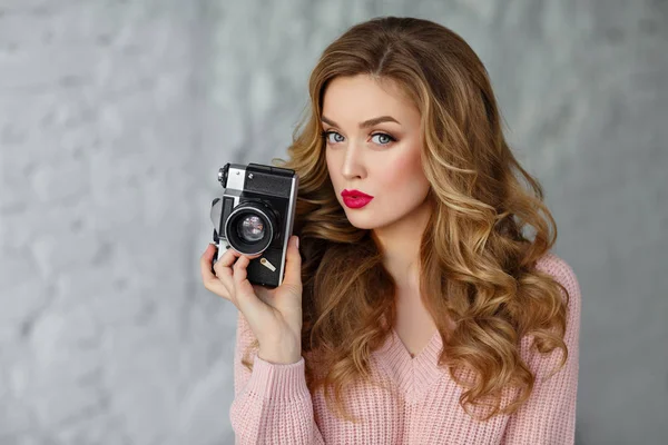 Beautiful blonde girl with a camera in hand. White background, c — Stock Photo, Image