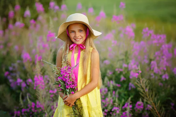 Een klein meisje in een gele jurk en muts, holding lila bloemen ik — Stockfoto