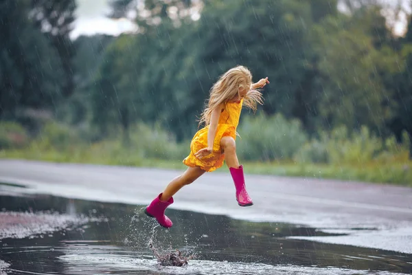 Ein kleines Mädchen in einem gelben Kleid lächelt und rennt durch den Pudding — Stockfoto