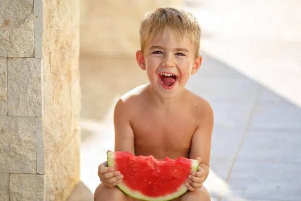 El niño come sandía roja y se ríe. En el verano, yo Imagen De Stock