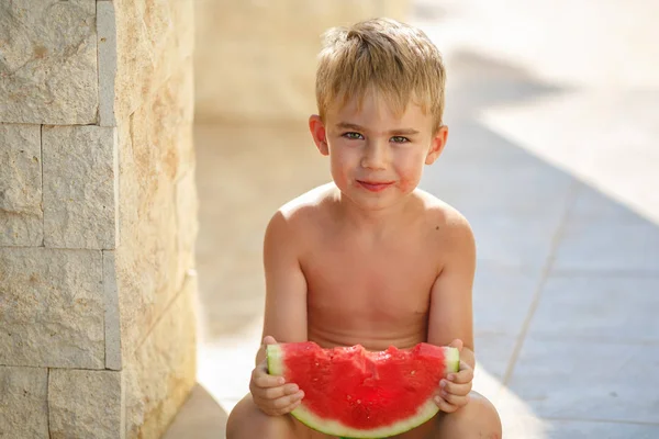 El niño come sandía roja y se ríe. En el verano, yo Imagen De Stock