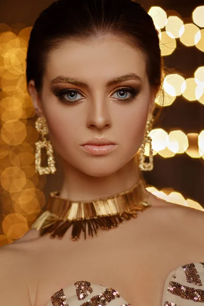 Retrato de una hermosa chica sexy con maquillaje en un vestido de oro en Imagen De Stock