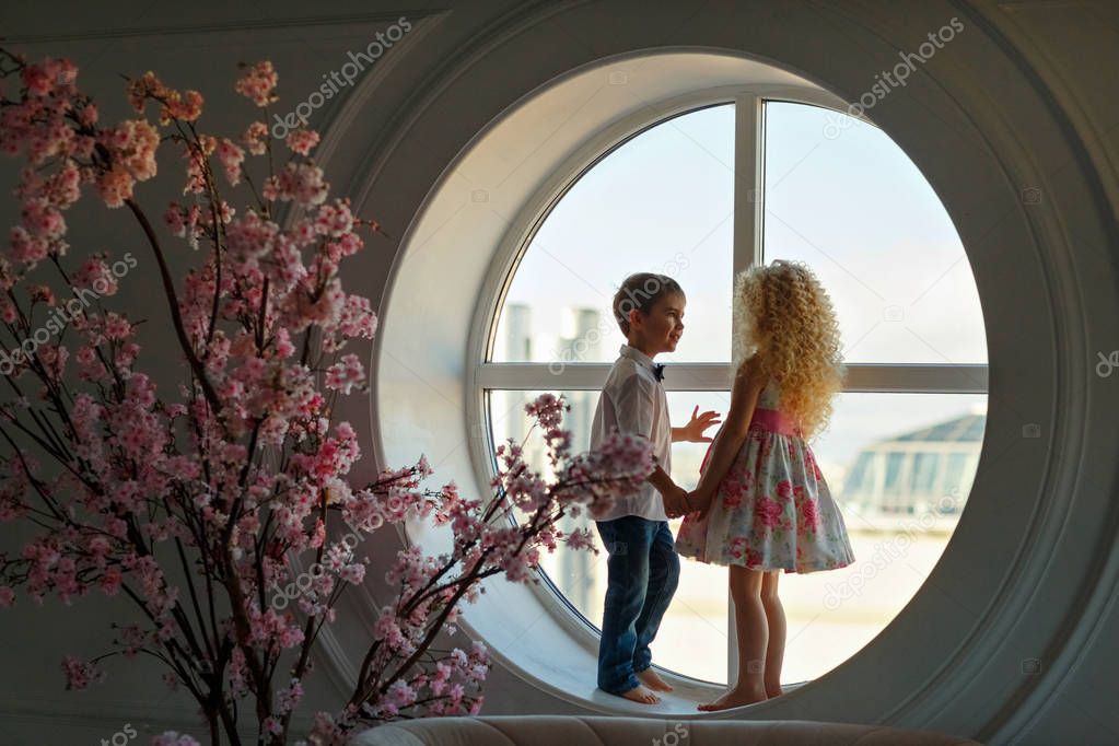 Charming cute little boy and girl blonde hold hands against the 