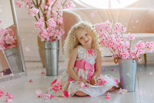 Little very cute curly blonde girl in a dress sits on the floor, — Stock Photo, Image