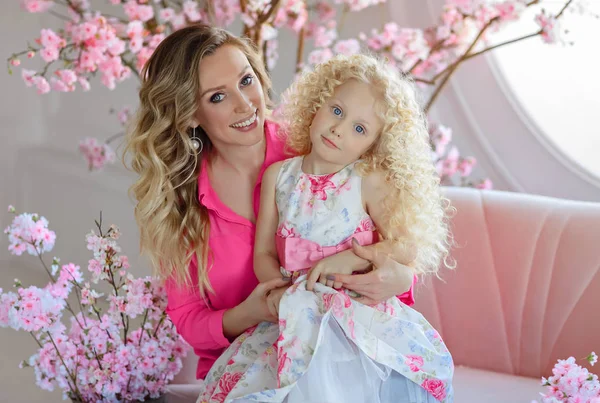 Schöne blonde Mutter umarmt eine sehr süße lockige blonde Tochter in einem — Stockfoto