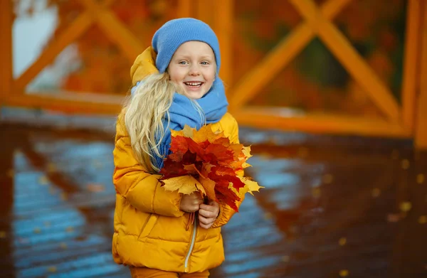 Frumos mic blonda fata cu ochi albaștri într-o jachetă galbenă o — Fotografie, imagine de stoc