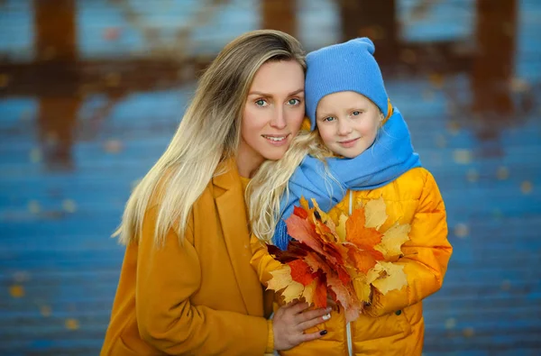 Мама і дочка блондинки з блакитними очима в жовто-синьому полотні. — стокове фото