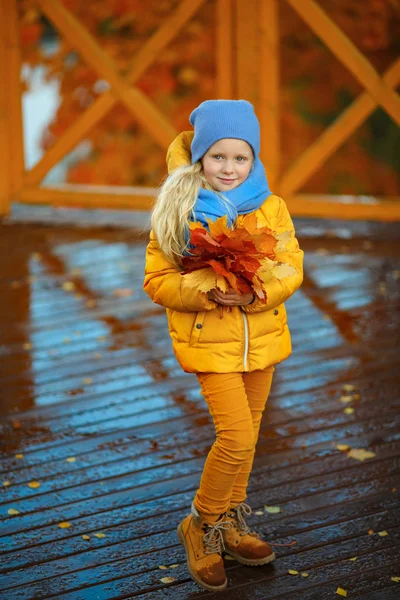 Frumos mic blonda fata cu ochi albaștri într-o jachetă galbenă o — Fotografie, imagine de stoc