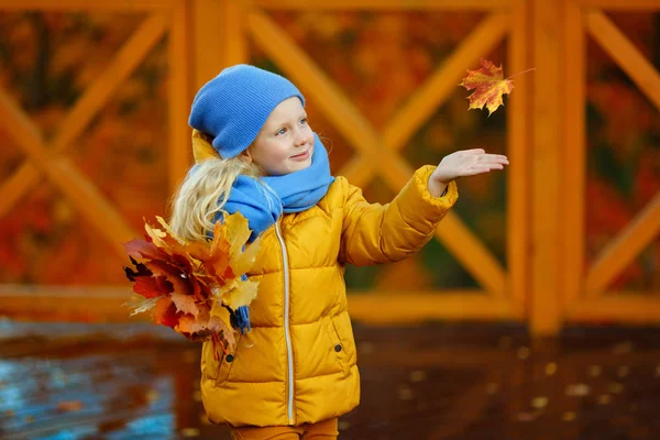 Vacker liten flicka blond med blå ögon, i en gul jacka — Stockfoto