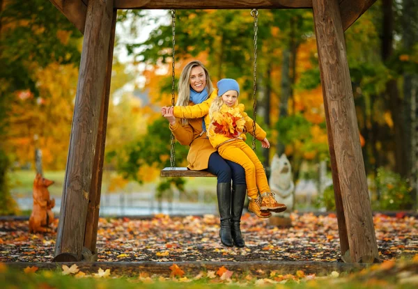 Мама і дочка блондинки в жовтому і синьому вбранні веселяться. — стокове фото