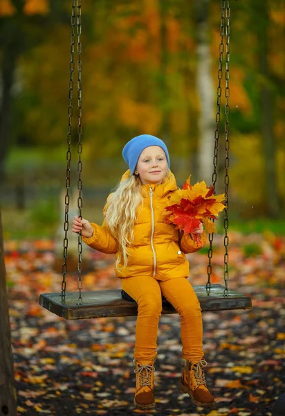 Mooi blond meisje met blauwe ogen, in een geel jasje — Stockfoto