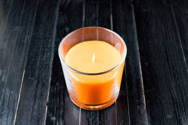 Portakal, balkabağı renkli mum ve siyah doğal ahşap masa arkaplanı. Cadılar Bayramı karanlık ruh hali.