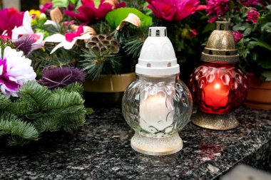 Mezarda beyaz ve kırmızı mezarlık mumları ve çiçekler. Azizler Günü. Katolik kilisesi tatili sırasında ölenleri hatırlamak..