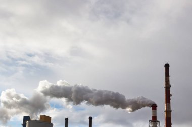 Duman ya da buhar yavaş yavaş uzun fabrika ya da elektrik santrali bacasından çıkıyor..