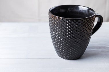 Gri doğal ahşap arka planda siyah modern kahve fincanı. Uzayı sola kopyala.