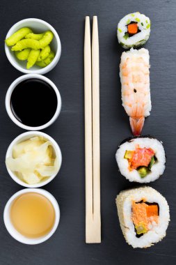 Tipik Asya mutfağı, siyah mutfak tabağına dizilmiş. Zencefil, Japon yaban turpu wasabi, soya ve balık sosu küçük beyaz kaselerde. Yemek çubukları. Suşi - futomaki ve nigiri.