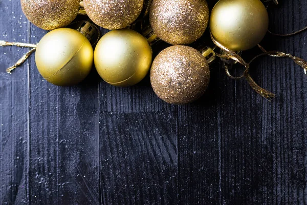 Sarı noel ağacı takıları siyah ahşap masada. Boşluğu en alta kopyala.