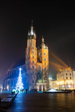 Krakow, Polonya 'daki ana meydandaki St. Mary Bazilikası. Geceleri yapay ışıklandırmayla görüş. Canlı renkler.