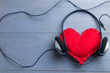 Sevgililer Günü 'nde kulaklıklı kırmızı ev yapımı kalp. Soyut müzik konseptine duyulan sevgi. Uzayı sola kopyala.