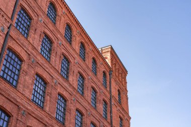 Polonya 'nın Lodz şehrinde mavi gökyüzüne karşı eski kırmızı tuğla kiracı evi veya fabrika binası.