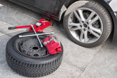 Yaz lastiklerinde kış tekeri arabanın yanında yatıyor. Mevsimlik lastik değişimi veya servis soyut kavramı.