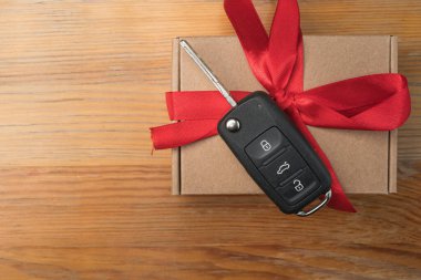 Kağıt kutuda araba anahtarı ve doğal ahşap masa arkasında kırmızı fiyonk. Noel ya da Sevgililer Günü hediyesi ya da şu anki soyut kavram.